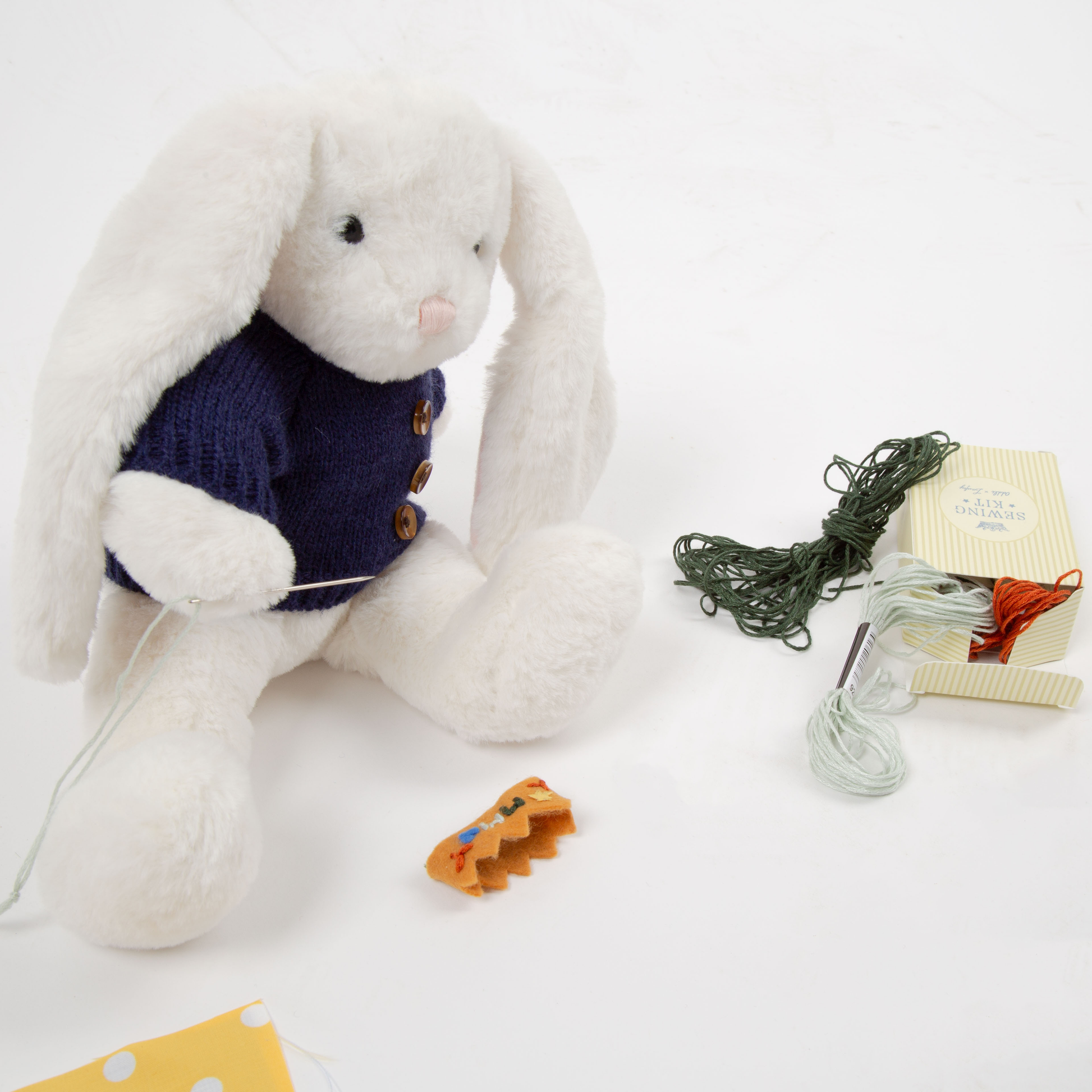 White plush bunny with a navy sweater on a white background