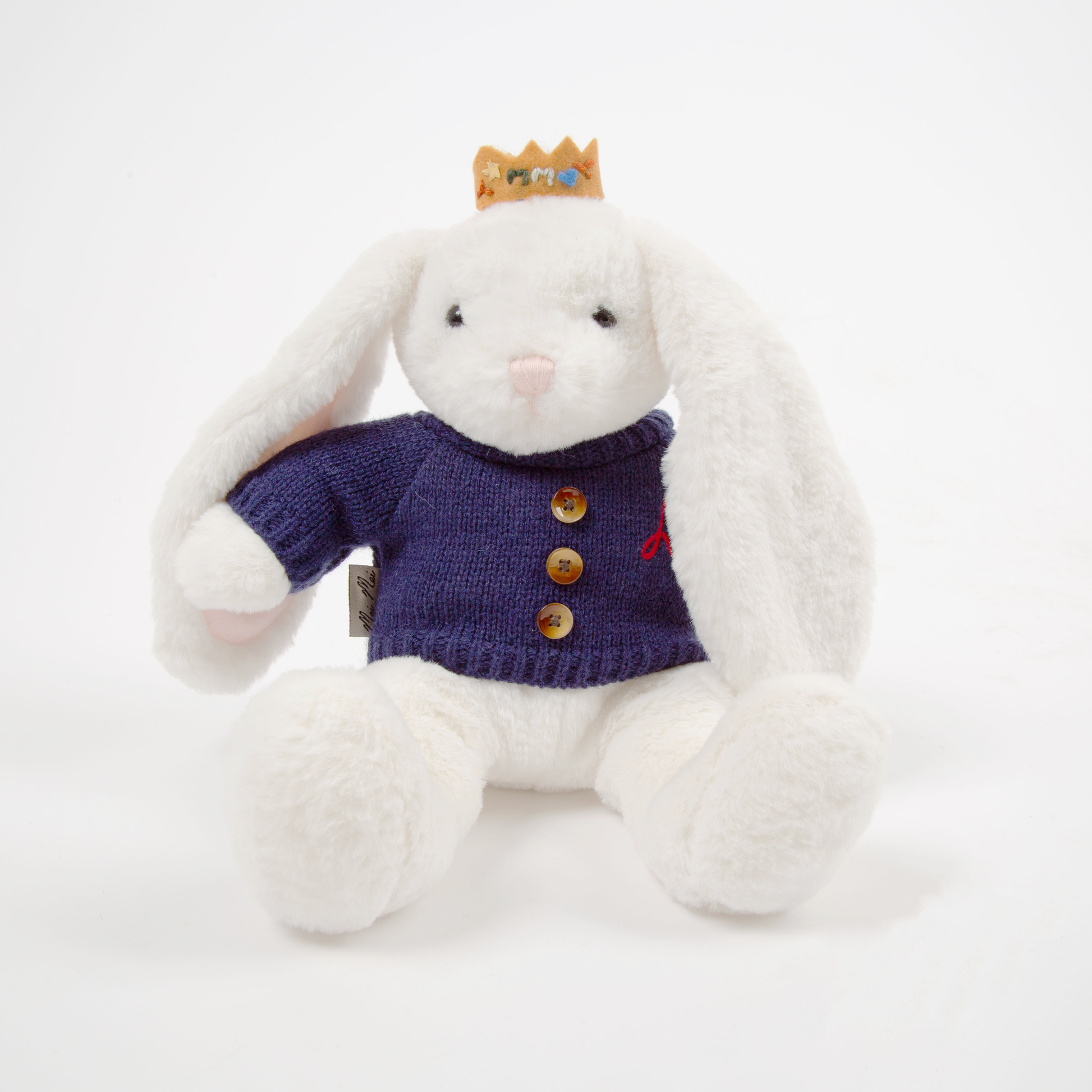 White plush bunny toy wearing a purple sweater with buttons on a white background