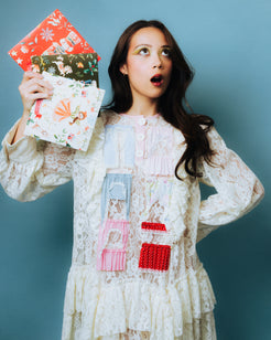 Laufey holding colorful Christmas 7" vinyl from the box set against a blue/gray background