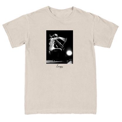 A light beige crewneck t-shirt featuring a black and white graphic print of a cellist on stage, with the name 'Loursy' printed in script below the image.