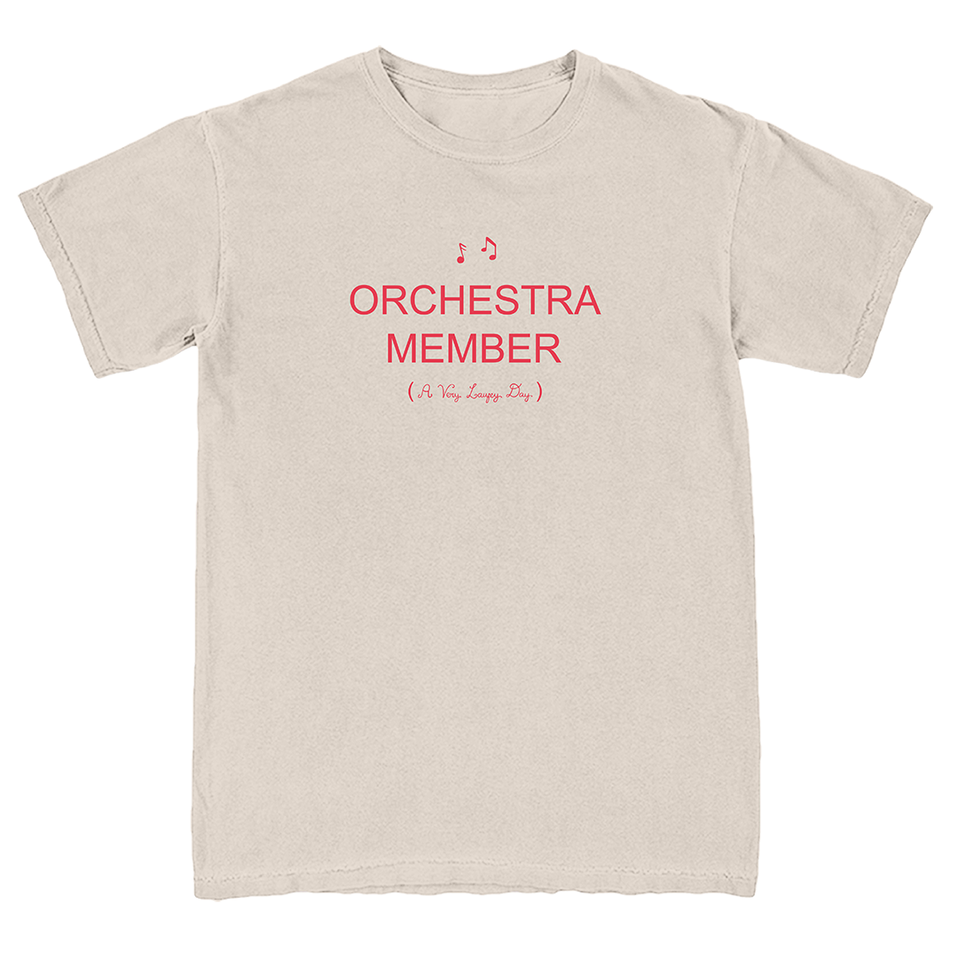 A light beige crewneck t-shirt with red printed text reading 'ORCHESTRA MEMBER (It's So Easyly Fun)' on the chest, displayed flat against a white background.
